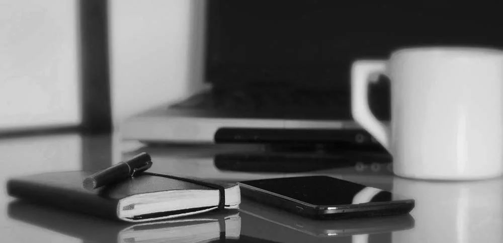 Computer, desk, cup, notebook, pen and mobile phone